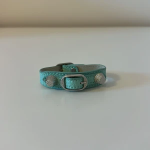 Turkost armband med silverdetaljer. Balenciaga liknande💗💗 - Snyggt turkost armband med silverfärgade detaljer. Armbandet har en justerbar rem och dekorativa runda nitar som ger en cool look. Perfekt för att ge din outfit en färgklick!