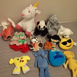 Samling av Gossedjur - En samling av olika mjukisdjur inklusive en enhörning, panda, och flera andra djur och figurer. Perfekt för barn eller som dekoration. Färgglada och varierande i storlek och form.