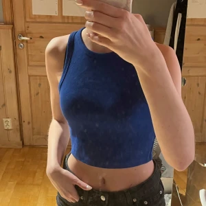 Blå ribbad linnetopp - Säljer en snygg blå ribbad linnetopp. Den är ärmlös och croppad, perfekt för varma dagar. Toppen har en enkel och stilren design som passar till många olika outfits. Pris går att diskutera. 