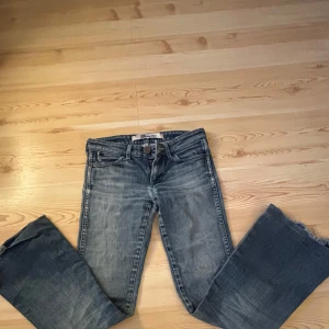 Lågmidjade bootcut jeans - Säljer ett par klassiska blå jeans från Wrangler med slitna detaljer och en bekväm passform. Innerben är 75 när jag har sytt upp dem men om man sprättar upp dem blir de 85 midjemått är 35 . Hål i grenen men går lätt att fixa och om man har på sig dem syns ingenting alls. PRIS GÅR ATT DISKUTERA❤️