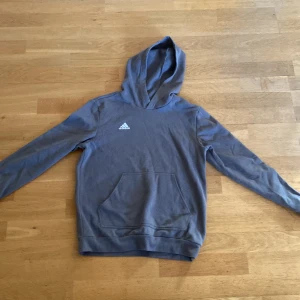 Grå/grön hoodie från Adidas - Säljer denna grön/gråa hoodie från adidas för att den har växt ut mig. Har använt den ett få tal gånger dvs 5-10. Hoodien har inga hål eller smuts fleckar. 