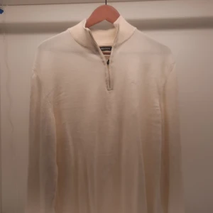 Vit tröja från J.Lindeberg - Säljer en stilren vit tröja från J.Lindeberg med dragkedja vid halsen. Tröjan har långa ärmar och en diskret logga på bröstet. Perfekt för en minimalistisk look.