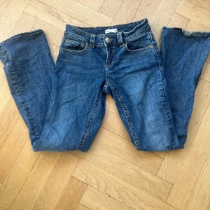 Blå jeans från Gina tricot  - Snygga blå jeans från Gina tricot storlek 36. De har en klassisk femficksdesign och knappdetaljer på bakfickorna. Jeansen är low waist bootcut och det är Gina tricots version av ”true religion” jeans och passar för vintern samt sommaren💕 priset kan diskuteras🥰