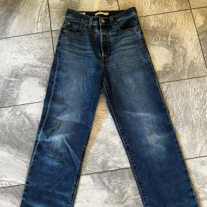 Levi's Ribcage Straight Jeans - Snygga Levi's Ribcage Straight jeans i en klassisk blå denim. Dessa jeans har en hög midja och raka ben, vilket ger en tidlös look. Perfekta för en avslappnad stil med en touch av vintagekänsla.