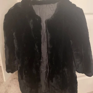 Svart pälsjacka - Säljer en snygg svart pälsjacka. Den är supermjuk och perfekt för kalla dagar. Jackan har långa ärmar och en klassisk passform. Perfekt för att hålla sig varm och stilren under vintern.