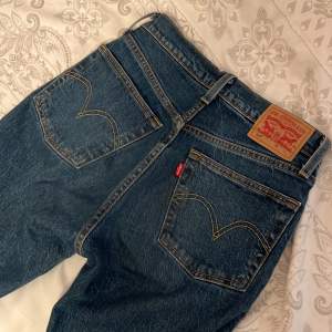 Ett par highwaisted, mörkblå Levis 501 jeans som är straighta i storlek W24, L29