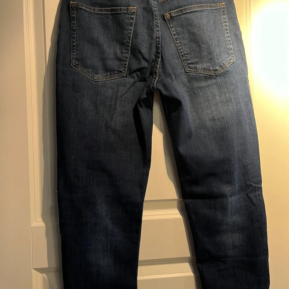 Säljer ett par snygga blå jeans med relaxed tapered fit. De är i storlek 38 och har en bekväm passform. Perfekta för vardagsbruk och kan matchas med nästan vad som helst. De har en klassisk femficksdesign och är tillverkade i ett slitstarkt denimtyg.. Jeans & Byxor.