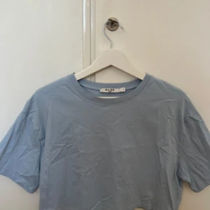 Ljusblå t-shirt från NA-KD - Säljer en ljusblå t-shirt från NA-KD. Den är enkel och stilren med korta ärmar och en normal passform. Perfekt för vardagsbruk eller sommarens varma dagar. T-shirten är i bomull och väldigt bekväm att ha på sig.