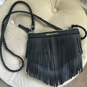 Svart väska med fransar - En jättesnygg väska som ej kommer till användning! Liten men får plats med t.ex mobil och plånbok. Bandet kan du ta av och på för att ha det som en clutch-väska ☺️ Bea skick men lite slitningar på ett ställe (sista bilden) 💝