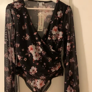 Blommig body från Newyorker - Blommig mesh body med ballongärmar. Dubbeltyg på fram och baksida. Passar M-L. Aldrig använd. Köparen står för frakt 💕