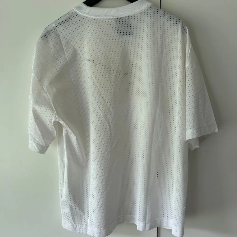 Säljer en vit mesh t-shirt från Nike i storlek S. T-shirten är gjord av ett lätt och luftigt material, perfekt för träning eller varma sommardagar. Den har en svart Nike-logga på bröstet och korta ärmar. T-shirten är i bra skick och har inga synliga skador. Passar både till träning och vardagsbruk. . T-shirts.