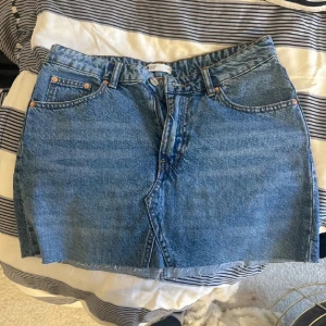 Blå jeanskjol från Perfect Jeans - Säljer en snygg blå jeanskjol från Perfect Jeans. Kjolen är kort och har en klassisk femficksdesign med två framfickor och två bakfickor. Den har en dragkedja och knapp framtill. Perfekt för både vardag och fest! 💙