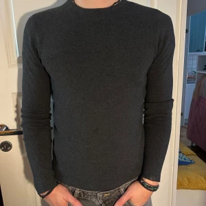 Mörkgrå Långärmad Tröja - En mörkgrå långärmad tröja i normal passform. Tröjan är enkel och stilren, perfekt för vardagsbruk. Storlek S men passar som M. Modellen är 182 cm och väger 75 kg. Pris går att diskuteras!
