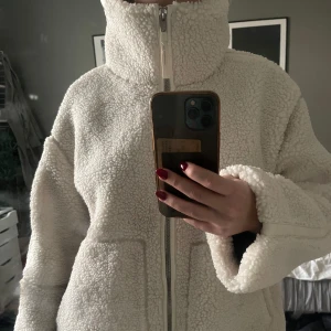 Vit teddyjacka med dragkedja - Super fin vinterjacka från H&M som är helt slutsåld överallt!! Nyskick då den endast är använd en gång, storlek L men sitter perfekt oversized på mig som är 172cm