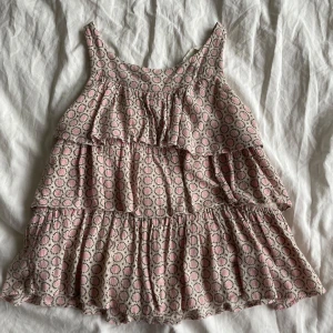 Mönstrad topp från H&M💗 - Söt klänning från H&M med volanger och ett prickigt mönster i rosa och beige. Perfekt för varma dagar med sin luftiga design och ärmlösa stil. Passar som Xs💗