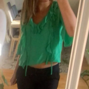 Blus - Säljer en snygg grön blus med volangdetaljer. Blusen har en lös passform och trekvartsärmar, perfekt för vår och sommar. Finns ej att köpa längre därav priset🥰