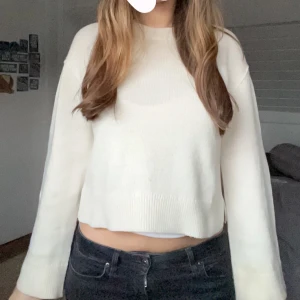 Vit croppad tröja - Säljer en stilren vit croppad tröja med långa ärmar och ribbad nederkant. Perfekt för en avslappnad look.