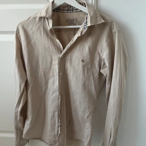 Burberry Skjorta - En riktigt fin beige Burberry Skjorta | Skick 9/10 | Fit slim som är väldigt snyggt för skjortor! Passar mellan 180-165 isch | Självklart äkta! Kom med frågor! 