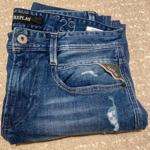 Blå jeans från Replay - Snygga blå jeans från Replay med snygga slitningar. Jeansen är perfekta för dagens trender och mode. Jeansen är knappt. Storleken är W29 och L32. Modell: Anbass 
