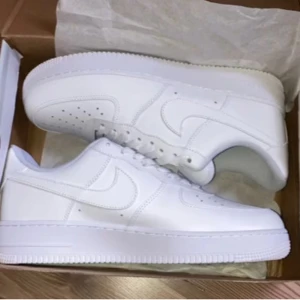  Nike Air Force 1 - Säljer ett par klassiska vita Nike Air Force sneakers. De har en stilren design med snörning och en robust sula. Perfekta för en casual look.