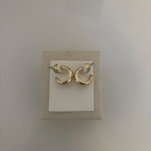 Guldörhängen i hoops  - Snygga guldörhängen i form av hoops. Perfekta för att ge en elegant touch till din stil. De är små och diskreta, vilket gör dem lätta att bära till olika tillfällen. Aldrig använt och helt ny.