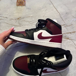 Nike Air Jordans i svart, vitt och vinrött - Snygga Nike Air Jordans i en stilren kombination av svart, vitt och vinrött. Skorna har klassisk snörning och den ikoniska Nike-loggan på sidan. Perfekta för dig som vill ha en sportig och trendig look. Pris kan diskureras vid snabb affär!!