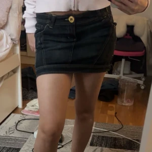 Blå  jeanskjol med knappdetalj - Trendig vintage blå jeanskjol med en guldfärgad knappdetalj framtill. Kjolen är i nytt skick, pris kan diskuteras💕är i storlek 32-34