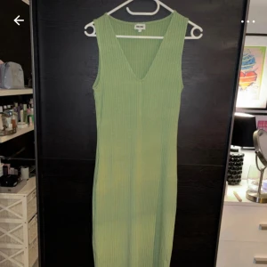 Grön ribbad klänning från Bubbleroom - Snygg grön ribbad klänning från Bubbleroom med v-ringning. Perfekt för en stilren look. Klänningen är ärmlös och har en lång design som ger en elegant siluett.
