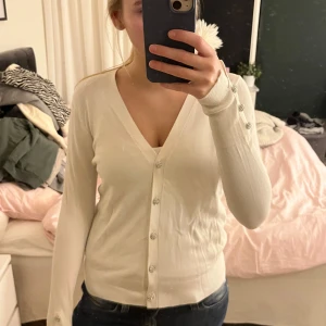 Vit kofta med glittriga knappar - Säljer en elegant vit kofta med glittriga knappar. Koftan har en v-ringad design och långa ärmar. Perfekt för att lägga till lite glamour i vardagslooken. Passar bra till både jeans och kjol. Skriv om ni har några frågor!💞