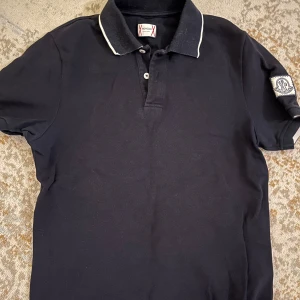 Mörkblå pikétröja från Moncler - Supersnygg piké från en äldre kollektion mellan Moncler och Gamme bleu. Därav den snygga loggan! Tröjan är i använt skick men fortfarande snygg, fräsch och inga skador. Säljer för att jag växt ut storlek s/xs passar för dig som är mellan 160 och 173. Vid frågor eller ytterligare bilder är det bara att höra av sig! Pris kan diskuteras!