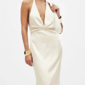 Champagnefärgad halterneckklänning - Elegant champagnefärgad halterneckklänning med öppen rygg och knytband i nacken. Klänningen har en smickrande passform och är perfekt för festliga tillfällen.