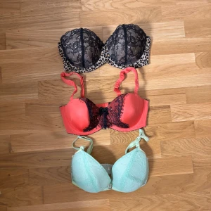 Tre olika bh:ar med spetsdetaljer - Säljer tre bh:ar i olika färger och mönster. En svart spetsbh med leopardmönster, en korallfärgad bh med svart spets och rosett, samt en mintgrön bh med spetsdetaljer. Perfekta för att lägga till lite färg och stil i garderoben.