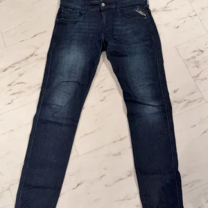 Mörkblå jeans från Replay - Snygga mörkblå jeans från Replay i modellen Anbass. De har en slim fit passform och klassisk femficksdesign. Perfekta för en stilren look.