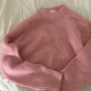 Rosa stickad tröja från H&M - Mysig rosa stickad tröja från H&M i storlek XS. Perfekt för kyliga dagar med sin mjuka och bekväma passform. Tröjan har långa ärmar och en ribbad krage samt muddar.