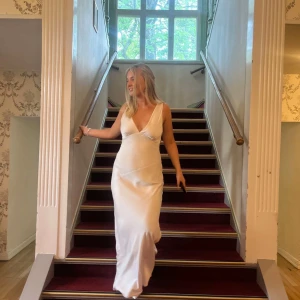 Champagnefärgad långklänning med v-ringning - Elegant silvrig/champagnefärgad långklänning med djup v-ringning och smala axelband. Jättefin öppen och djup i ryggen, perfekt som balklänning. Använd 1 gång så i nyskick. Den går ej att köpa längre på deras hemsida.