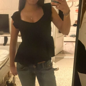 Svart topp från 157 - Snygg svart topp från 157 med volangdetaljer och v-ringning. Den är jättefin men blev ba lite för stor för mig. Perfekt för sommaren och gulliga armar