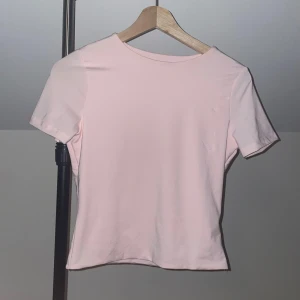 Ljusrosa kortärmad topp - Säljer en söt ljusrosa topp med korta ärmar. Perfekt för en avslappnad stil. Toppen har en enkel och stilren design. Sitter som skims 