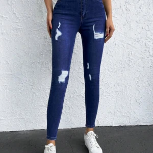 Skinny hög midja jeans storlek 27 nya - Snygga mörkblå skinny jeans med slitningar. De är högmidjade och har en tight passform som framhäver figuren. Perfekta för en trendig look.