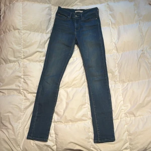 Blå jeans från Levi's - Säljer ett par klassiska blå Levi's jeans i modell skinny. De är högmidjade och har en snygg tvätt med fem fickor och knappgylf. 