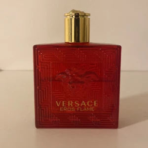 Versace Eros Flame Parfym - Säljer en elegant Versace Eros Flame parfym i en fyrkantig röd flaska med guldlock. Flaskan har ett stilrent mönster och den ikoniska Versace-loggan. Perfekt för den som vill ha en doft med karaktär och stil. Det är typ 70 procent kvar av den 