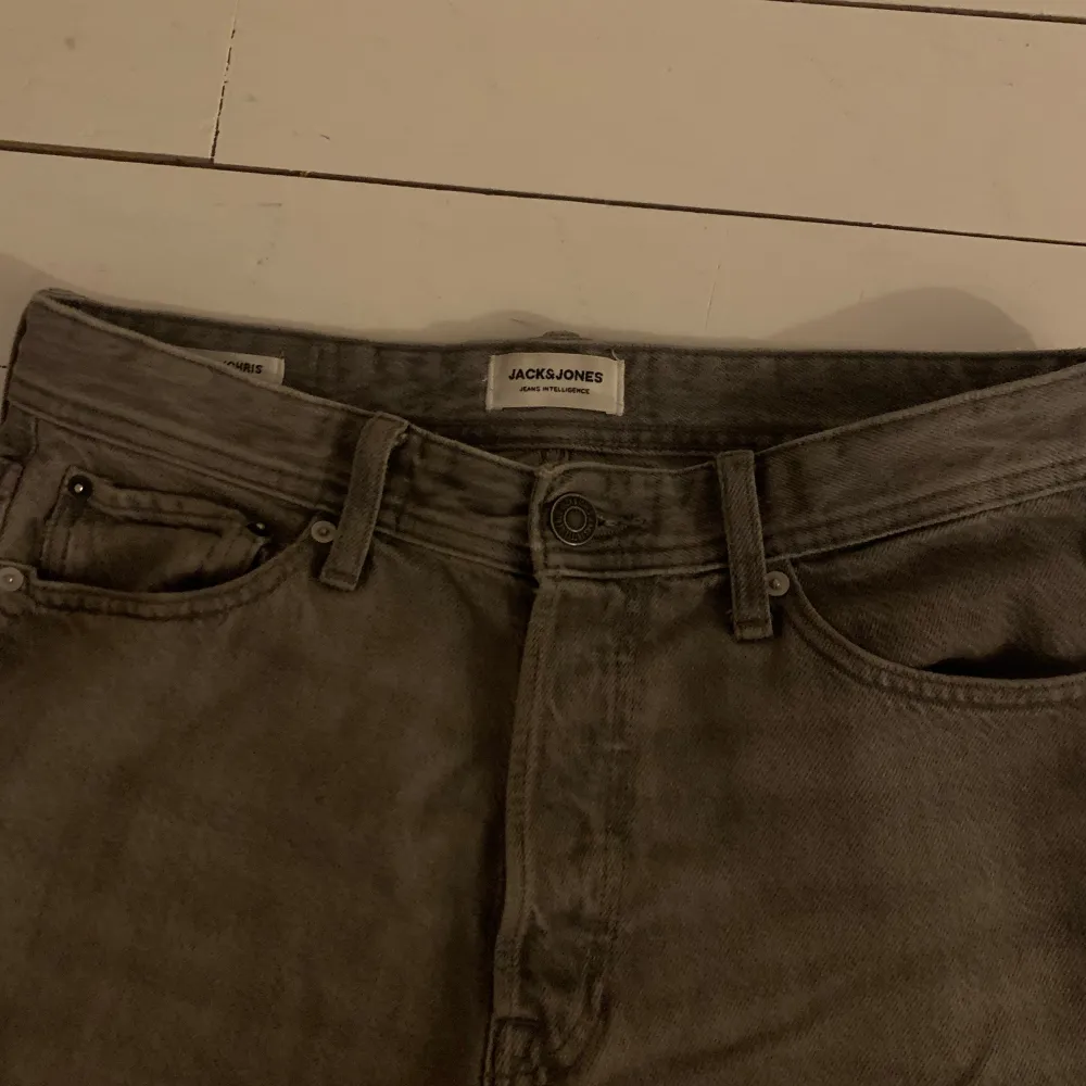 Säljer ett par grå jeans från Jack & Jones i bra skick. De har en klassisk femficksdesign med knapp och dragkedja framtill. Perfekta för både vardag och fest!. Jeans & Byxor.