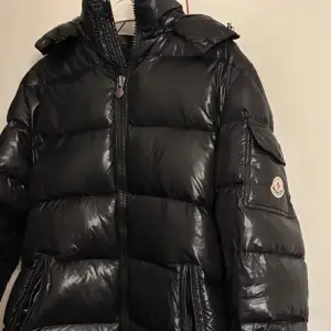 Säljer en snygg svart pufferjacka från Moncler i mycket bra skick. Jackan är perfekt för vintern med sitt quiltade mönster och långa ärmar. Den har en dragkedja framtill och en cool Moncler-logga på ärmen. Perfekt för att hålla sig varm och stilren under kalla dagar! Storleken är en 4a som motsvarar M/L ! Scanna för monclers hemsida går genom att scanna loggan med mobilen!  