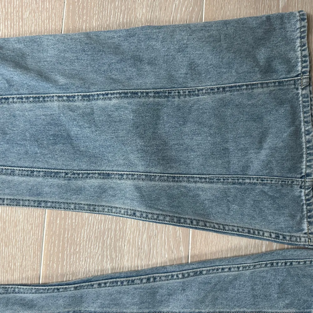 Säljer ett par snygga ljusblå bootcut jeans från H&M. De är tillverkade av 20% återvunnen bomull och 3% återvunnen polyester. Perfekta för en avslappnad stil med en modern twist. Passar bra till både vardag och fest! Nyskick med lapp kvar. De är helt slutsålda i butik och online.. Jeans & Byxor.