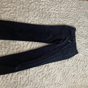 Svarta byxor från Juicy Couture - Säljer ett par snygga svarta byxor från Juicy Couture. De har en klassisk design med normal passform och är perfekta för både vardag och fest. Byxorna är tillverkade i ett mjukt material som ger en bekväm känsla hela dagen. Perfekta för höst och vinter!