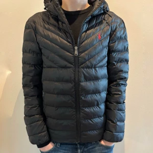 Svart dunjacka från Polo Ralph Lauren - Tvärsnygg Polo Ralph Lauren Jacka. Modellen heter Terra Chevron Insulated, och är köpt ny för 4395kr. En varm och skön jacka som passar perfekt nu till vintern. Inte några slitage alls på jackan, inga tecken på användning, helt enkelt mycket fint skick. Storlek XS. 