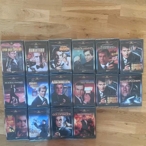 James Bond VHS-samling - Säljer en samling av klassiska James Bond-filmer på VHS. Inkluderar titlar som 'Leva och låta dö', 'Diamantfeber', 'Ur dödlig synvinkel' och 'Goldfinger'. Perfekt för Bond-fans och samlare av retrofilmer. Alla kassetter är i bra skick och kommer i sina originalfodral med plast på! Vi kan diskutera priset 
