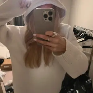 Säljer en supermysig vit stickad hoodie som är perfekt för kyliga dagar. Den har en avslappnad passform och långa ärmar, vilket gör den idealisk för både höst och vinter. Huvan ger extra värme och stil. Använt en gång och slutsåld i xs💗