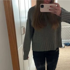 Grå stickad tröja - Säljer en mysig grå stickad tröja med ribbade detaljer vid ärmslut och nederkant. Köpt på arket, knappt använd ingen defekt 