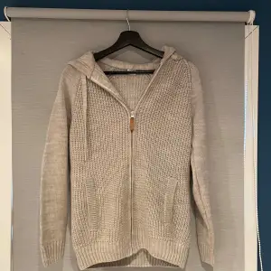 Mysig beige stickad hoodie perfekt för kyliga dagar. Den har en praktisk dragkedja framtill och en skön huva. Långärmad med ribbade muddar för extra komfort. Perfekt för både höst och vinter! Skriv vid minsta fundering!                    Mvh. Vilgot