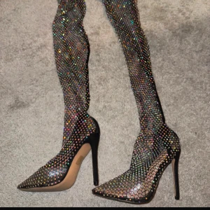 Glittriga stövletter med spetsig tå - Snygga glittriga stövletter med hög klack och spetsig tå. Perfekta för en festkväll när du vill sticka ut! De har ett glittrande mönster som fångar ljuset och ger en lyxig känsla.